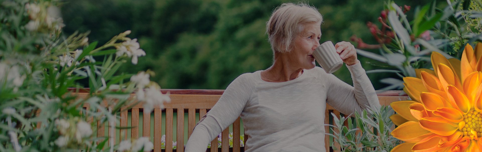 an older woman sitting on a bench drinking coffee