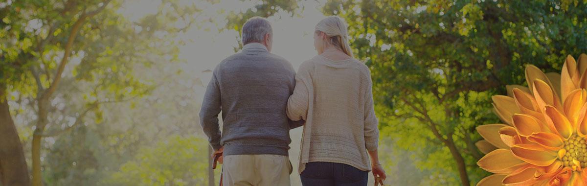 an elderly man and a young woman walking a path together