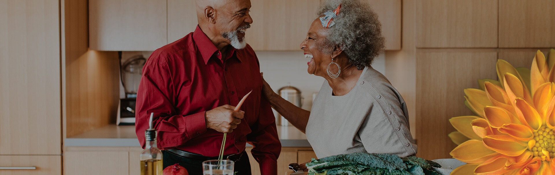 two seniors smiling and preparing a meal