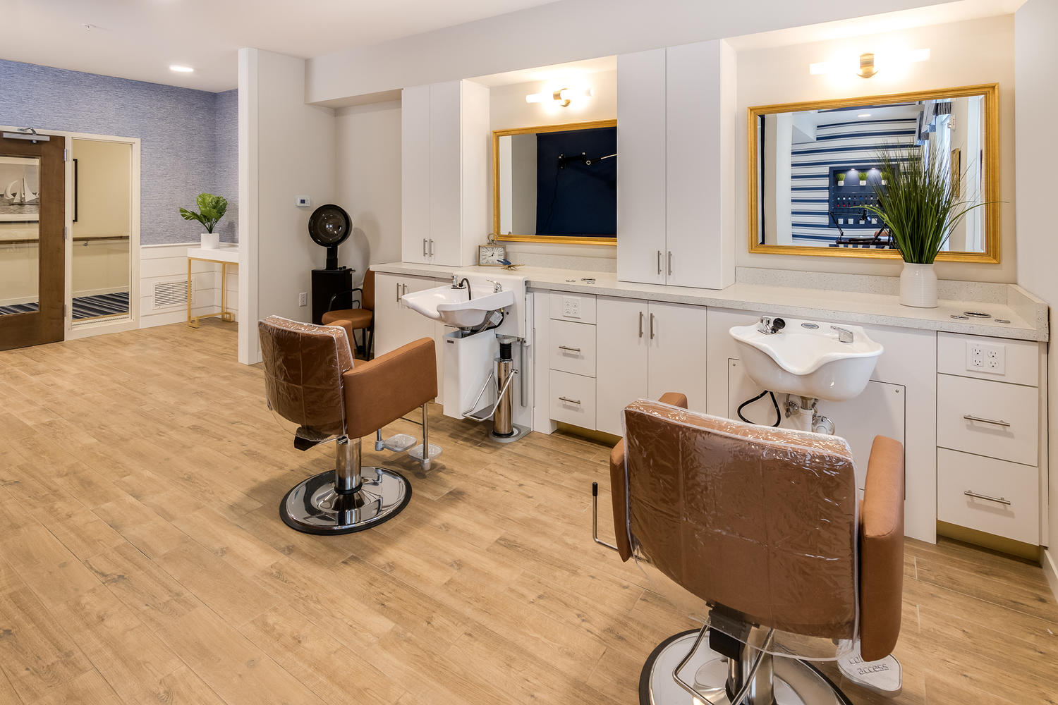 Salon chairs sitting in front of sinks, with mirrors on the walls in front of the chairs.