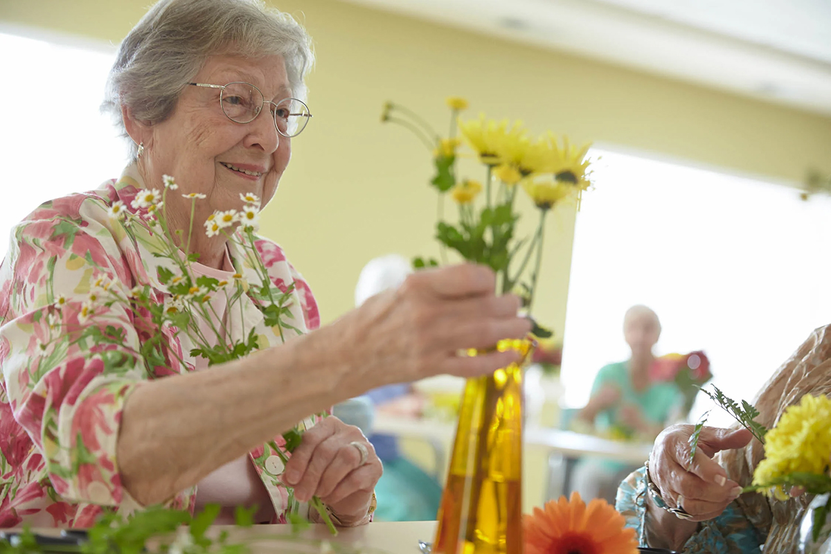 an elderly woman arranging flowers