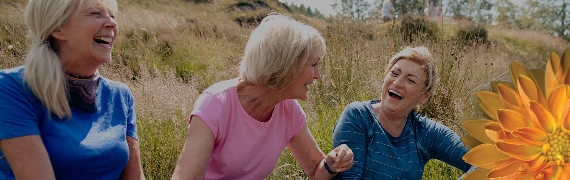 three women laughing happily in front of a field