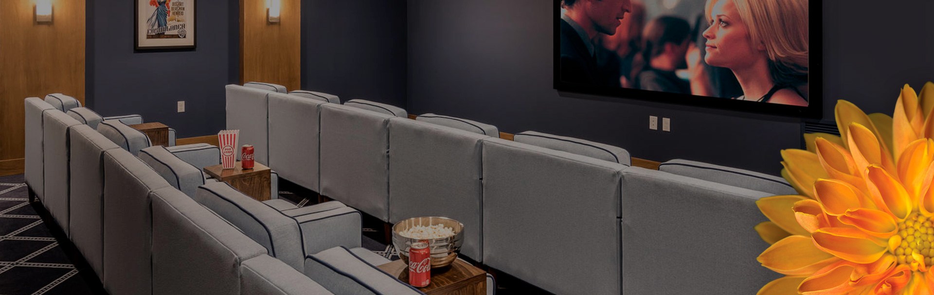 Two lines of chairs sitting in front of a tv on the wall, with popcorn and soda sitting on a table between the chairs.