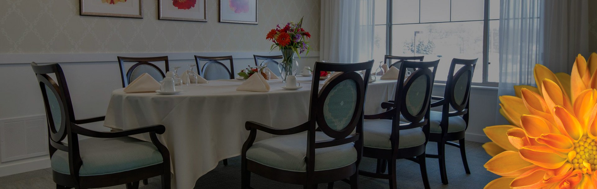 Dining room table with chairs around it, and flowers in the middle of it