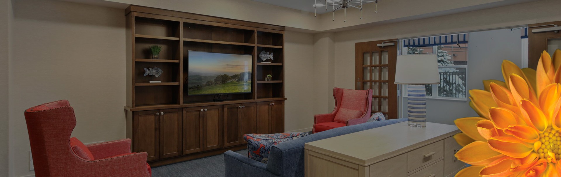 Living room with a few red chairs, a blue couch, and a bookshelf with a tv on it against the wall.