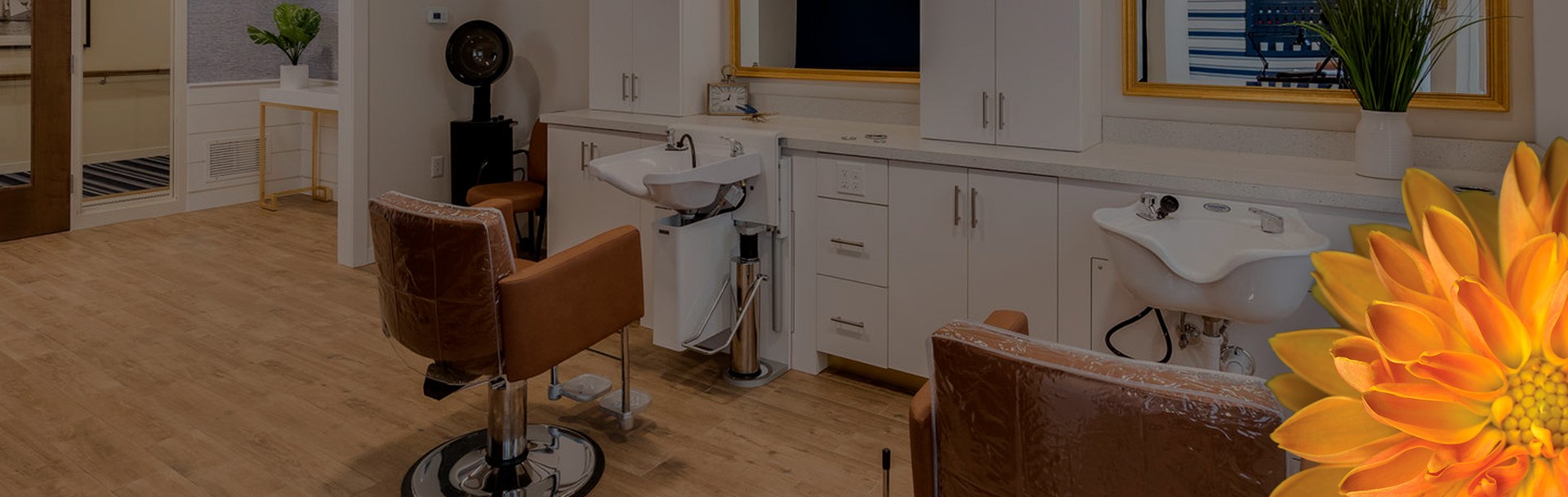 A room with a few salon chairs, sinks in front of those chairs, and mirrors on the wall.