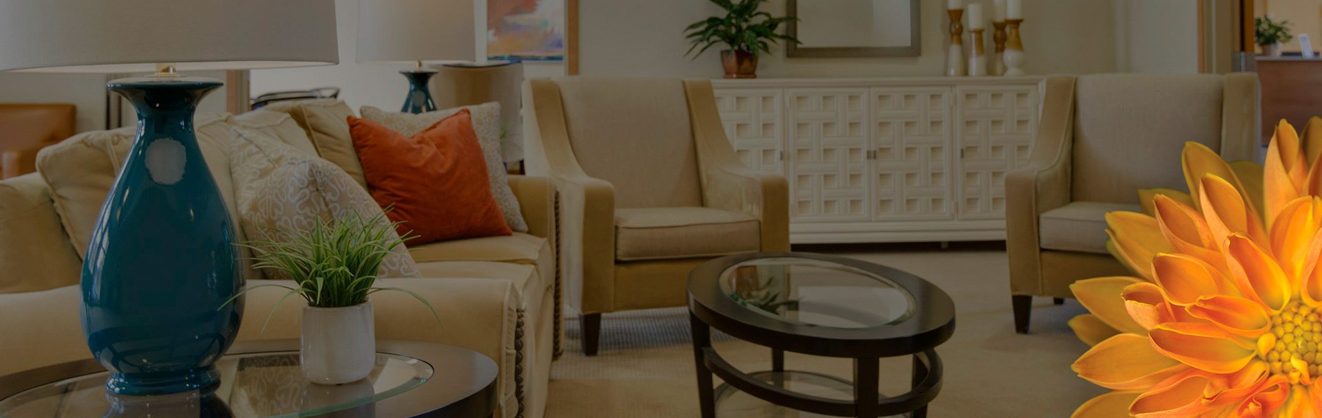 A living room setting with a blue vase sitting on a table, and many tan chairs sitting in a circle.