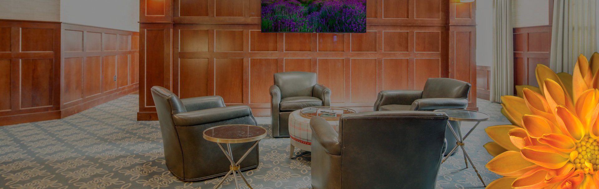 Living room setting with chairs sitting around a table, and a tv mounted on the wall