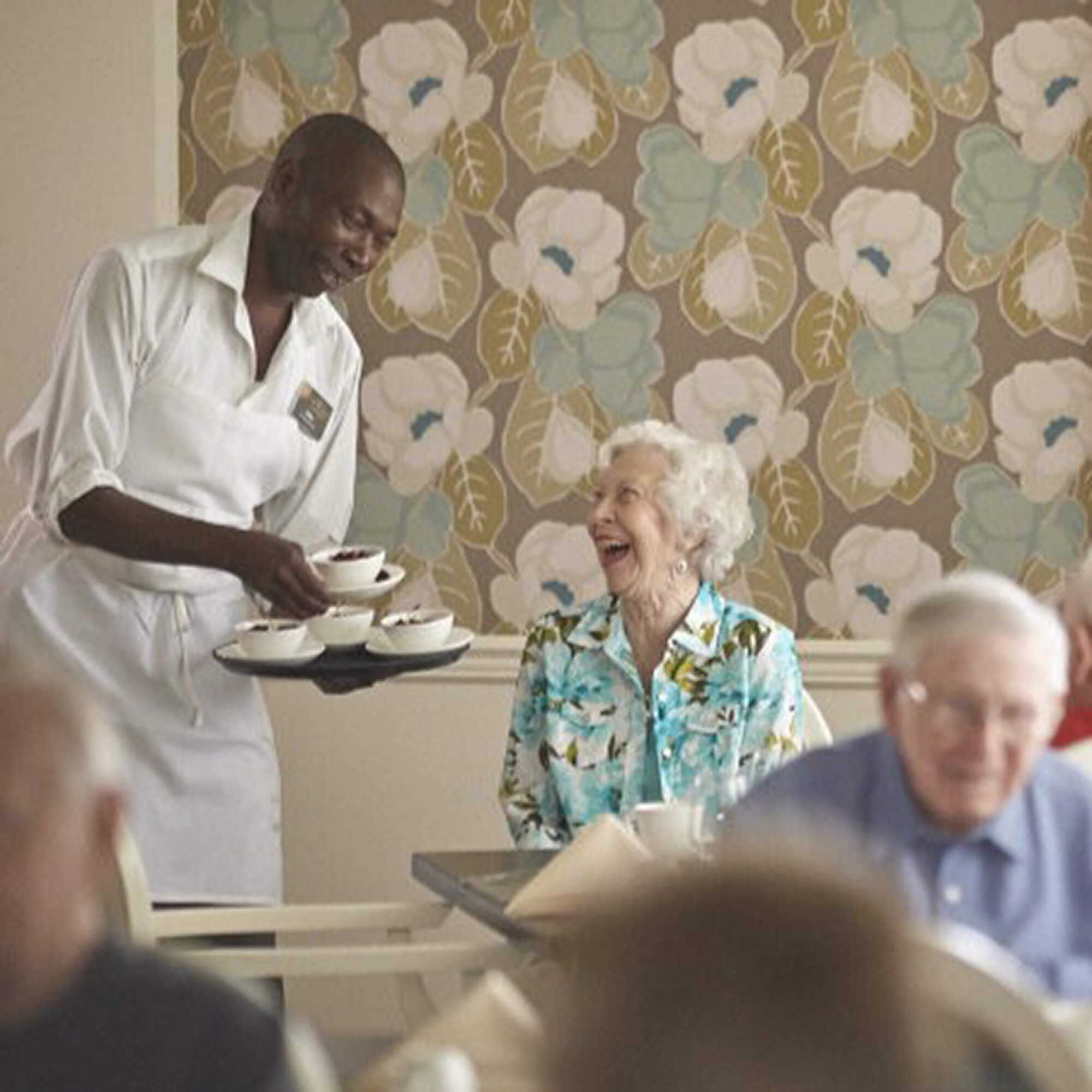 a team member serving food to residents and smiling