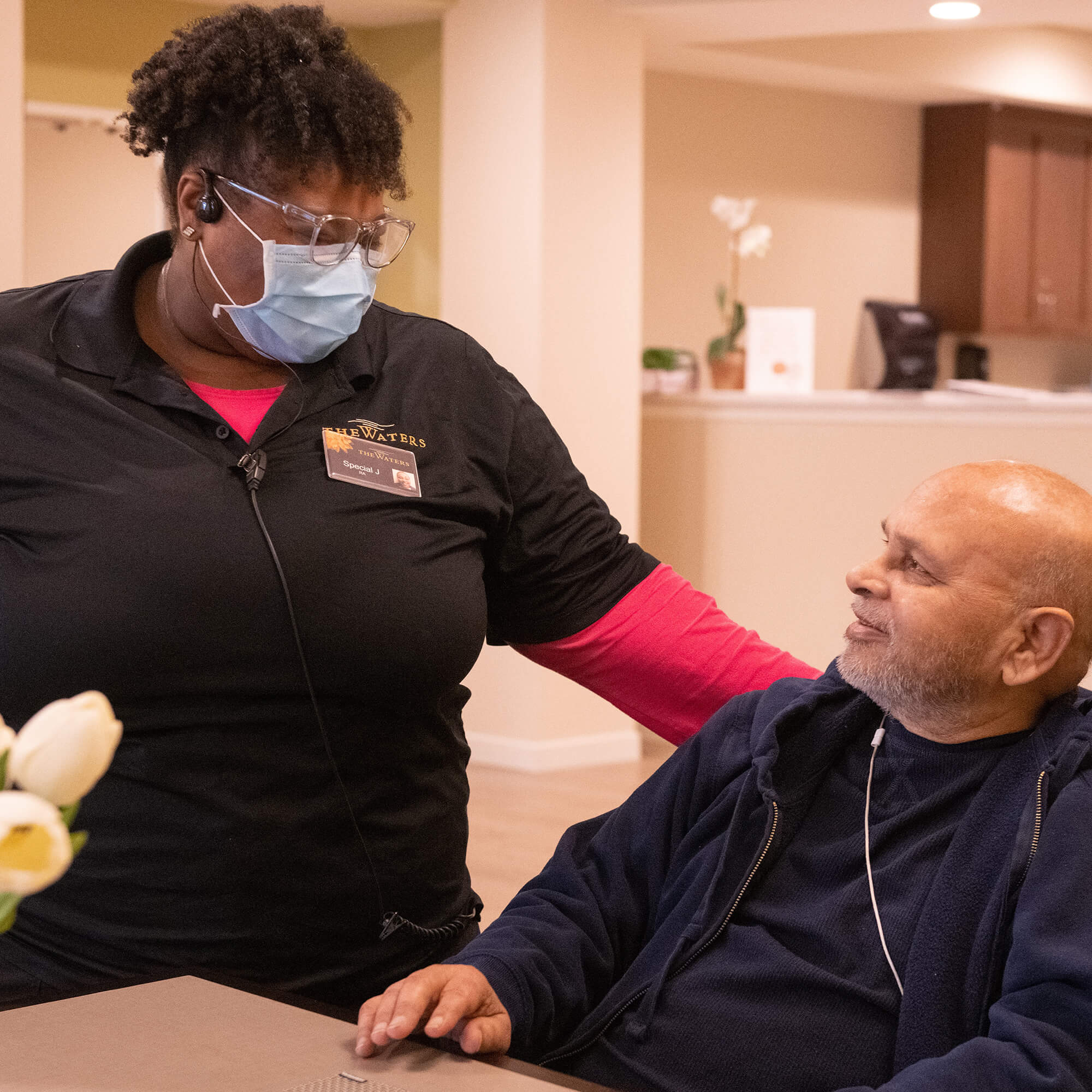 a female team member patting a resident on the shoulder