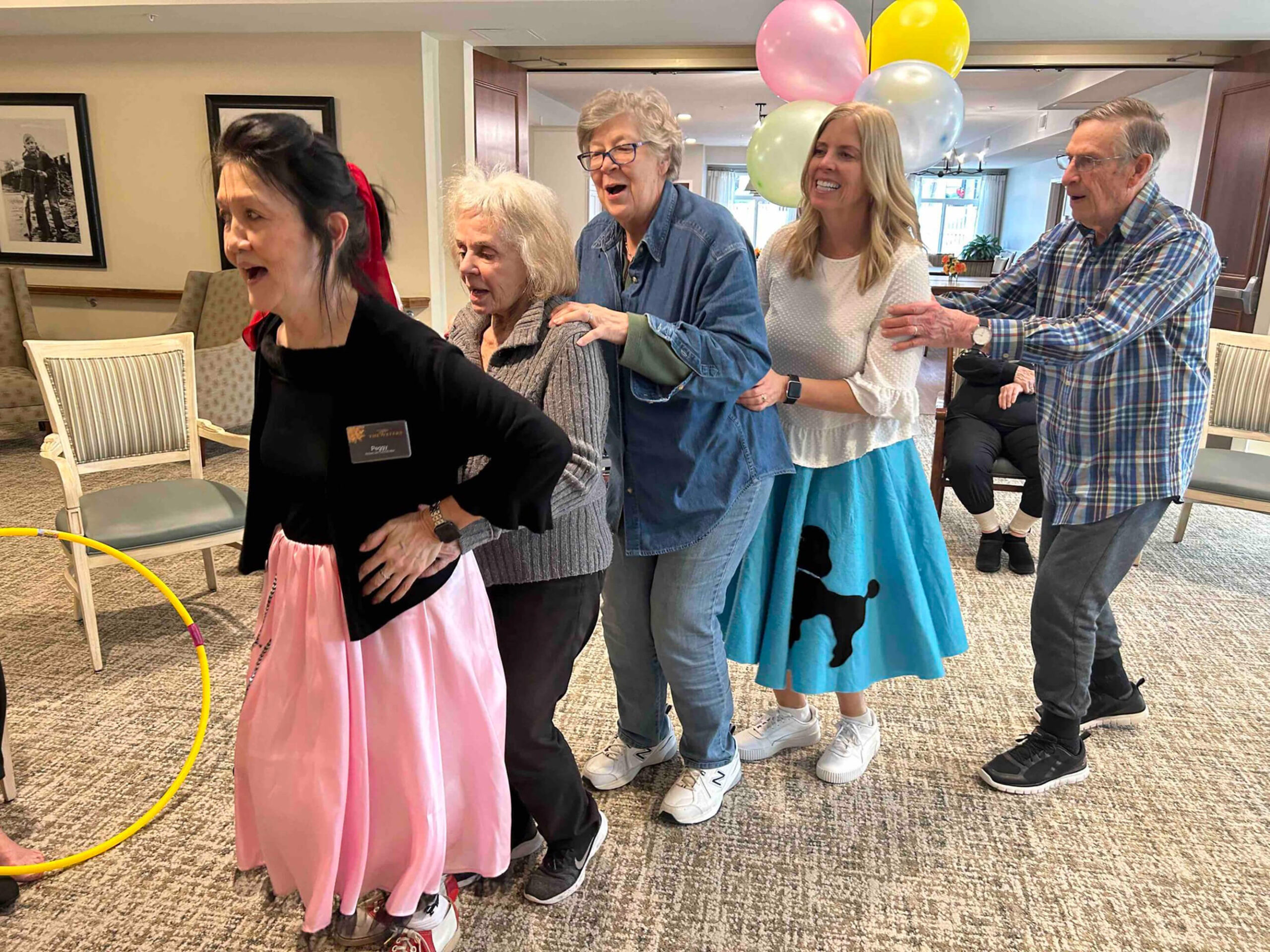 Seniors dancing at a themed party in Edina, laughter and balloons adding to the fun.