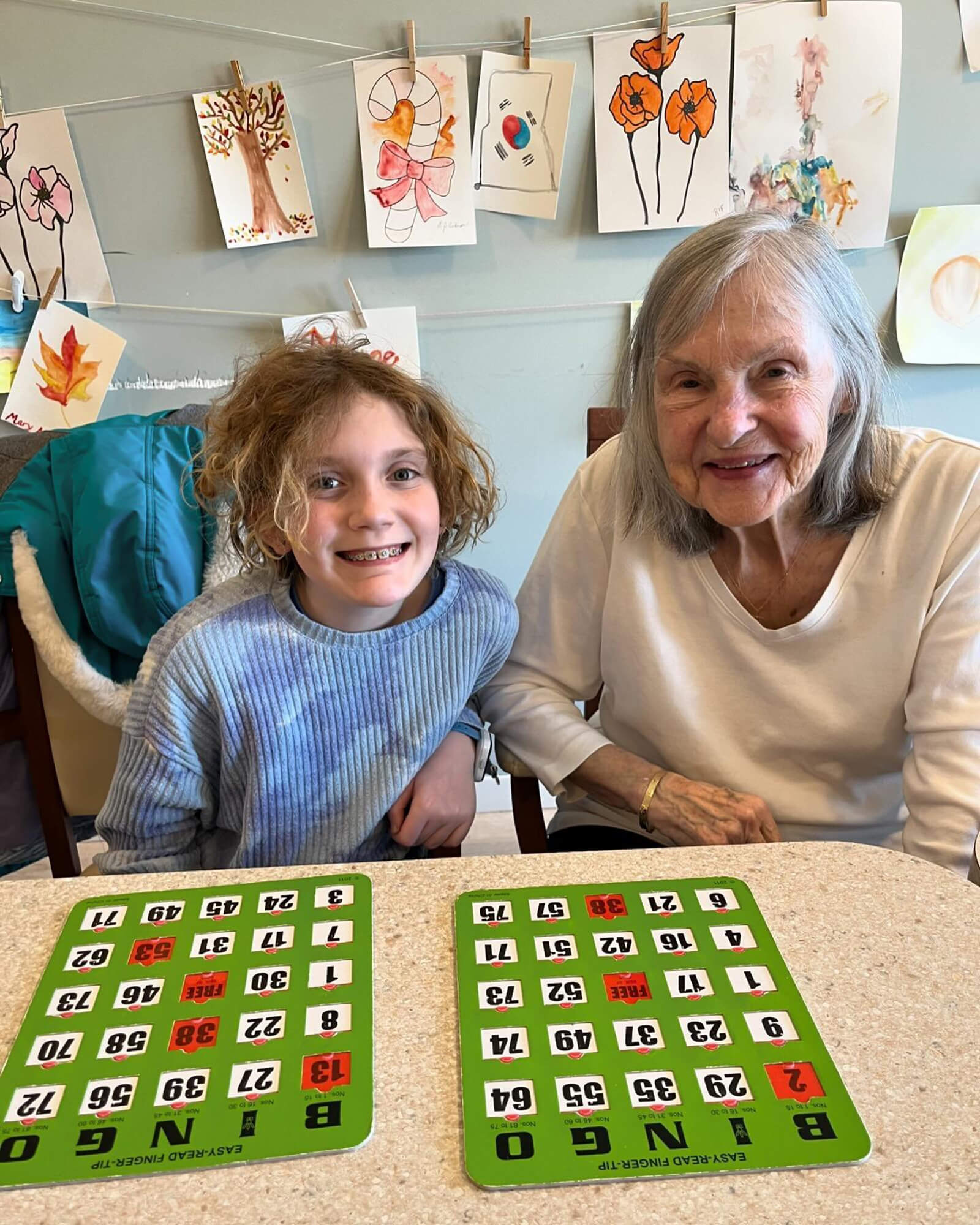 Smiling child and senior woman enjoying a bingo game together in Edina, MN.