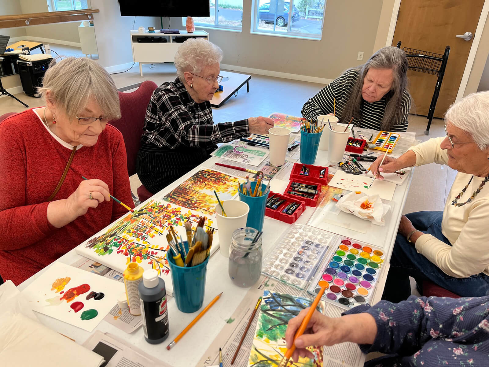 Elderly residents focused on painting during an art class at The Waters on 50th, expressing creativity and artistry.