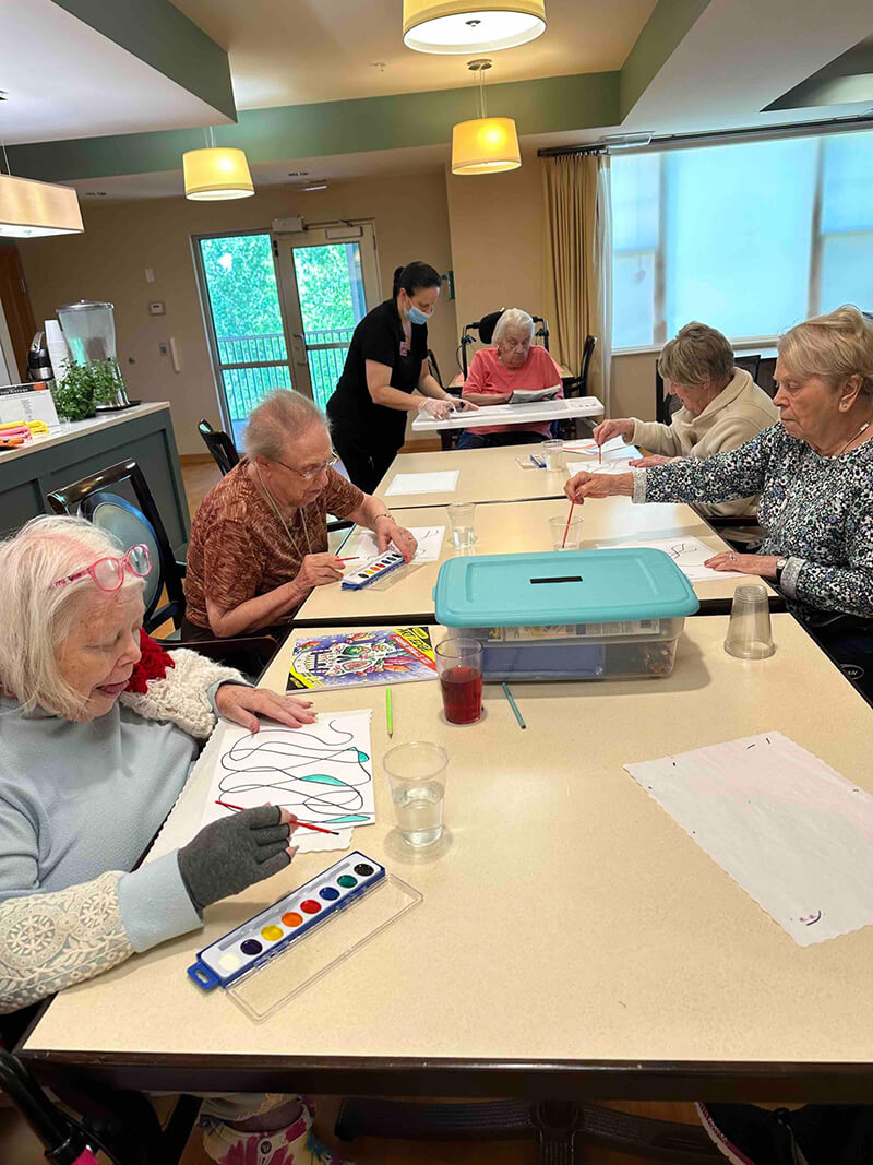 Seniors at The Waters of Oakdale deeply engaged in a painting class, highlighting the community's focus on creative expression and lifelong learning.