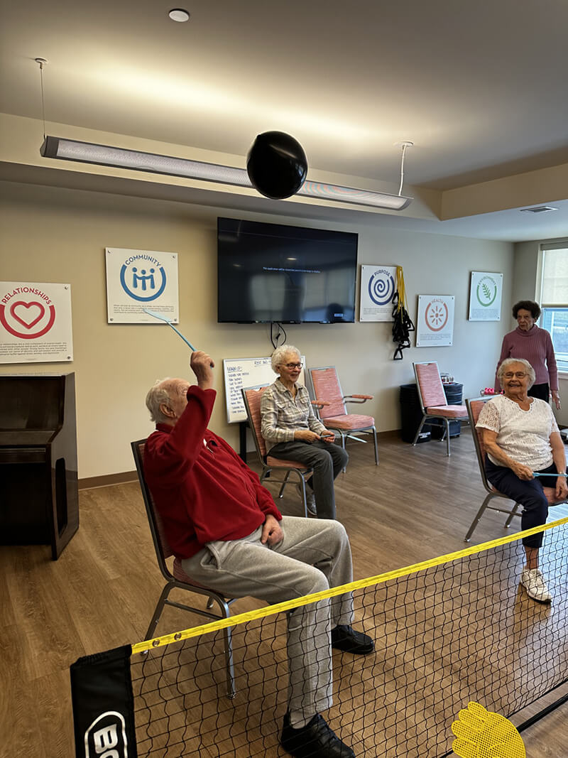 Seniors at The Waters of Wexford engaging in a fun balloon volleyball game, enhancing community interaction.