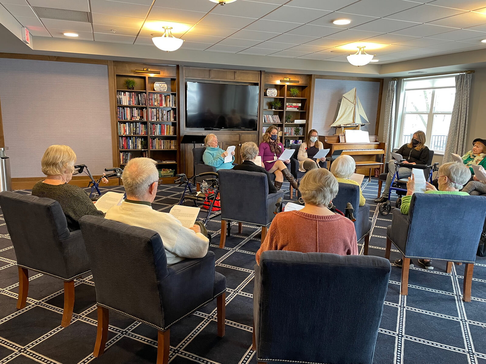 Elderly residents participating in a book club discussion at The Waters of Excelsior, fostering a community of learning and engagement.