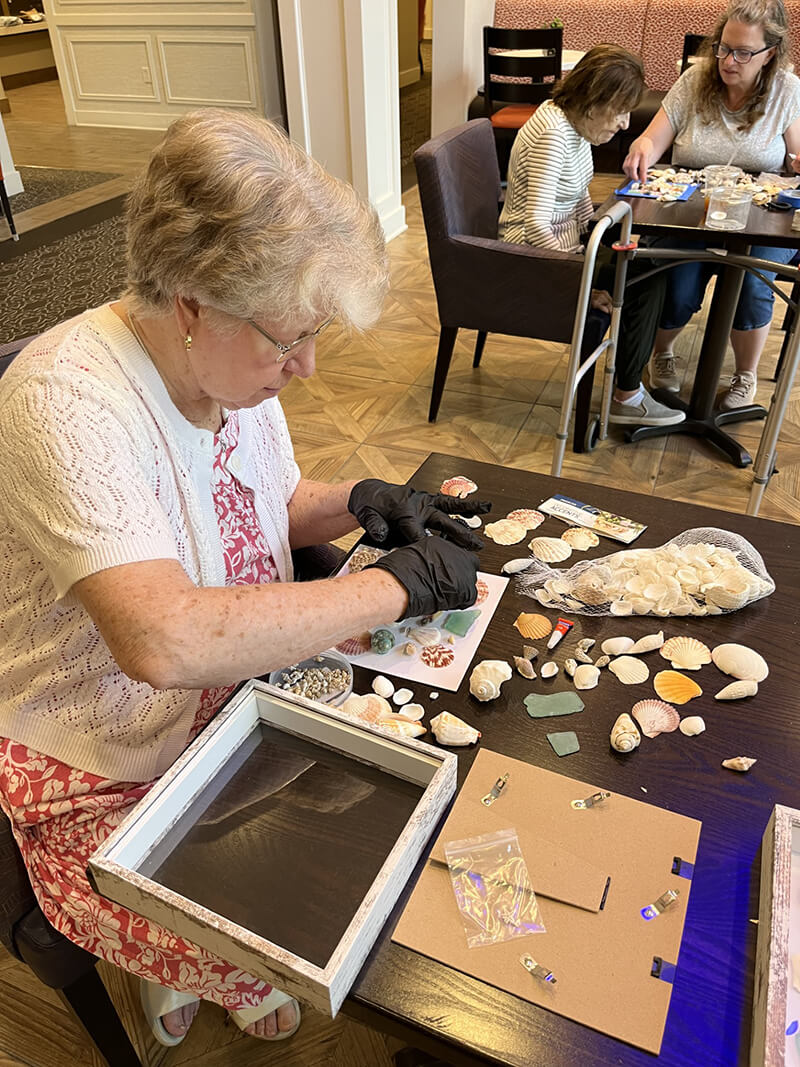 Elderly individuals at The Waters of Wexford engaging in a creative shell crafting workshop, showcasing their artistic skills.