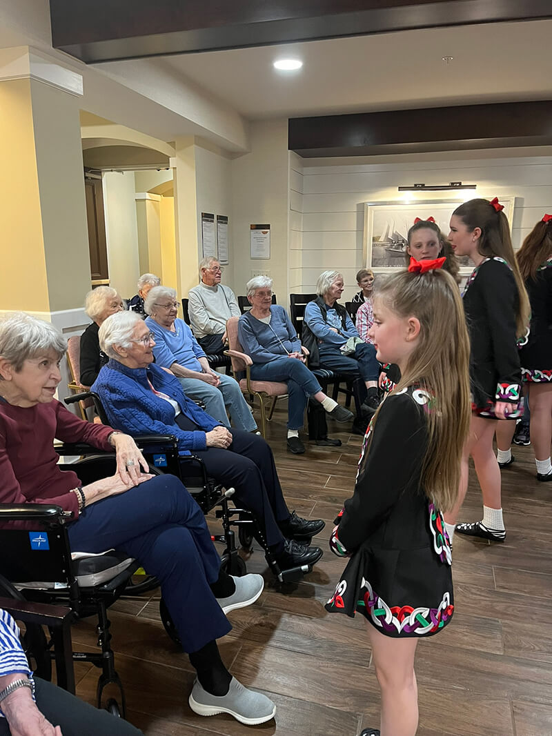 Young performers presenting a cultural dance to an engaged audience of seniors at The Waters of White Bear Lake.