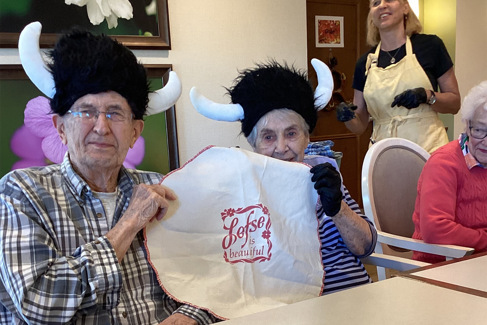 Seniors at The Waters on Mayowood having a joyful time wearing whimsical hats, showcasing the community's vibrant spirit.