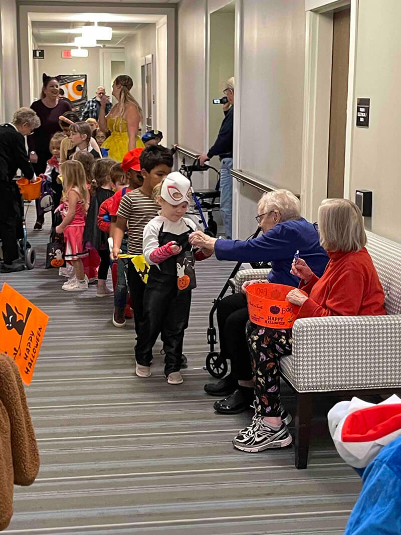 Residents handing out candy to children during a Halloween event at Oak Creek.