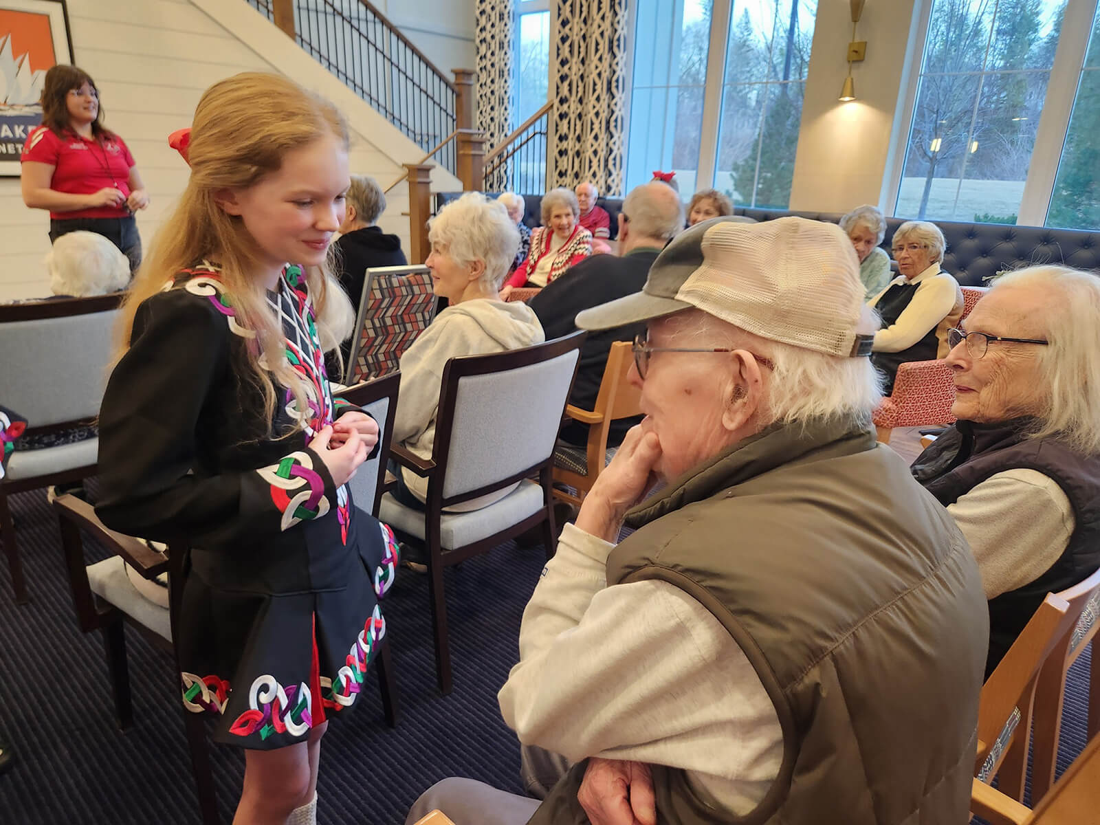 A heartwarming intergenerational interaction at The Waters of Excelsior, where a young volunteer shares a conversation with an attentive senior resident.