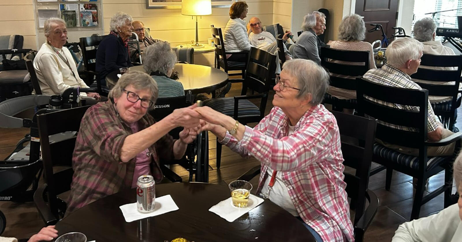 Two senior residents sharing a hand holding moment in the lounge area at The Waters of White Bear Lake