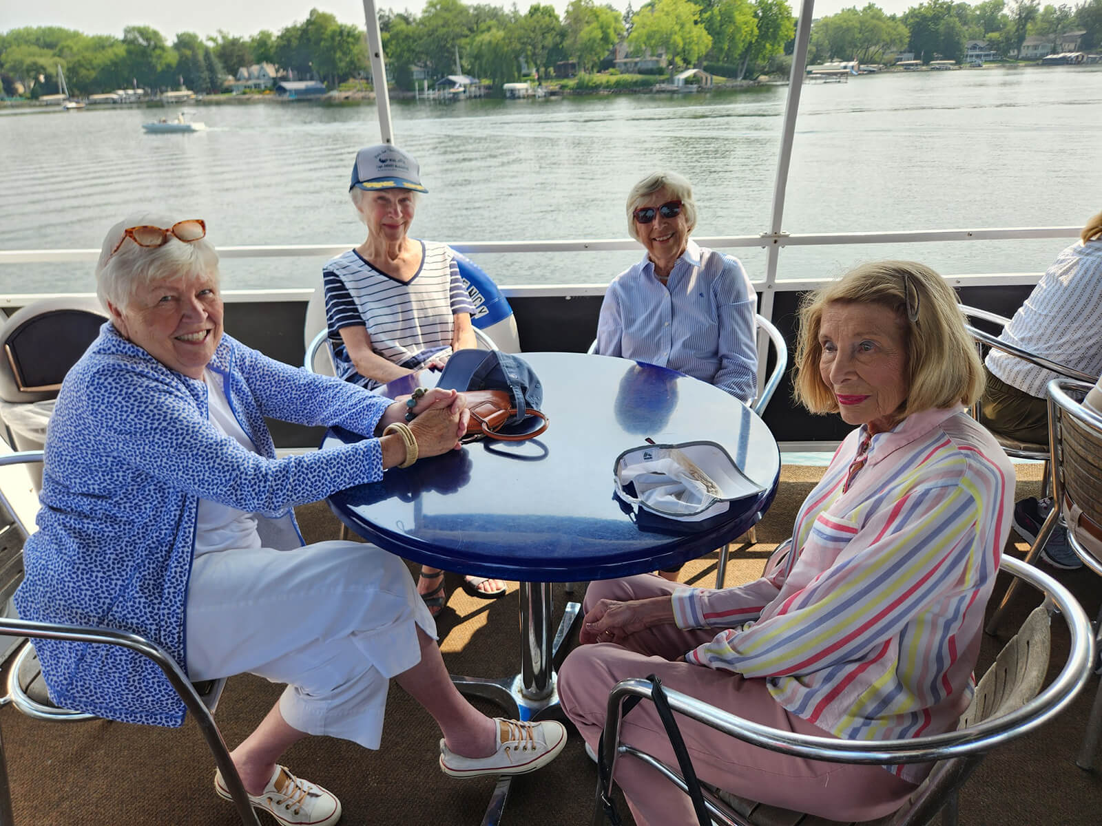 Residents of The Waters of Excelsior enjoying a scenic lake cruise, sharing smiles and conversation on a sunny day, encapsulating the vibrant senior lifestyle.