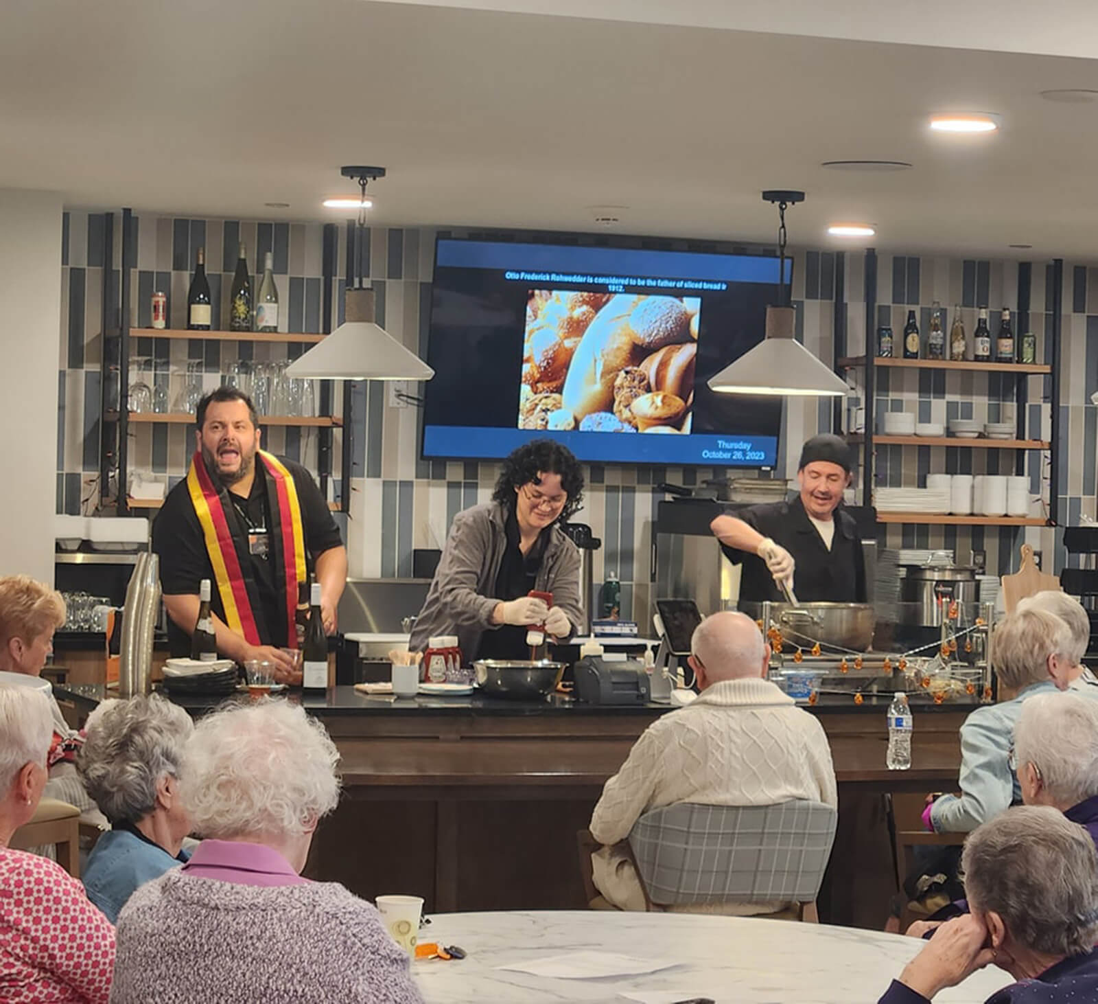 Seniors at The Waters of Pewaukee enjoying a live cooking demonstration, part of the community's diverse and engaging activity program.