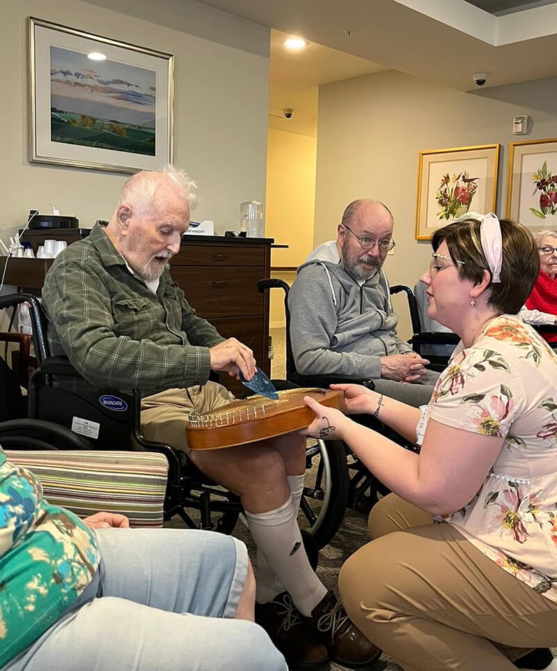 Senior man playing a lap harp during a music therapy session.