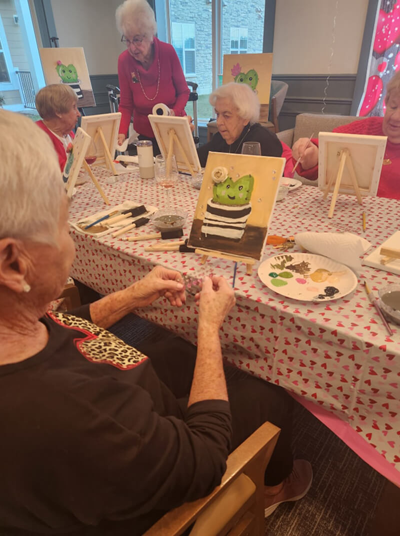 Elderly participants enjoying a painting class at The Waters of Pewaukee, focused on creating whimsical caterpillar artwork.