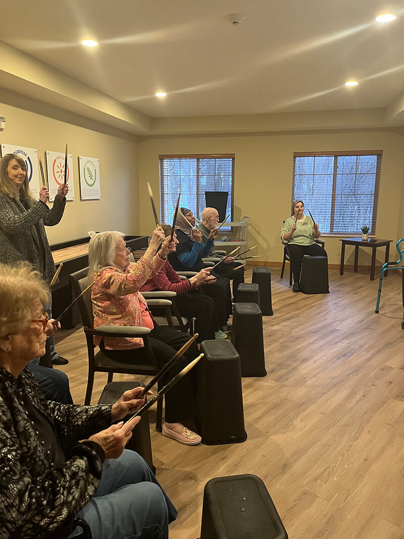 Senior residents participating in a rhythmic drumming exercise class in Plymouth.