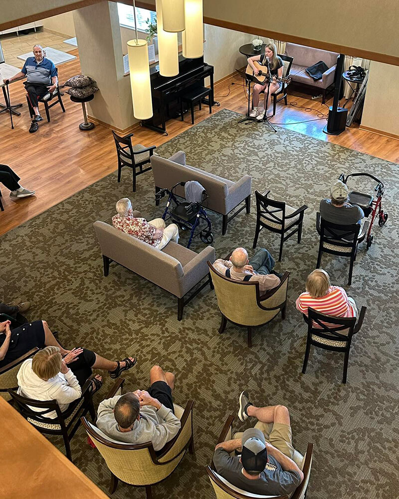 Elderly residents of The Waters of Oakdale gathered in the lounge to enjoy a live music performance, fostering cultural enrichment.