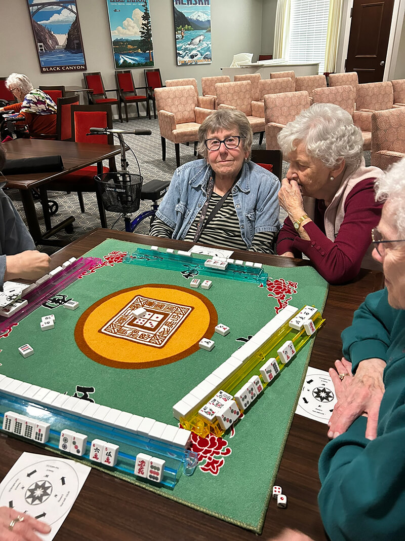 Group of senior residents playing Mahjong in the community area at The Waters of White Bear Lake.