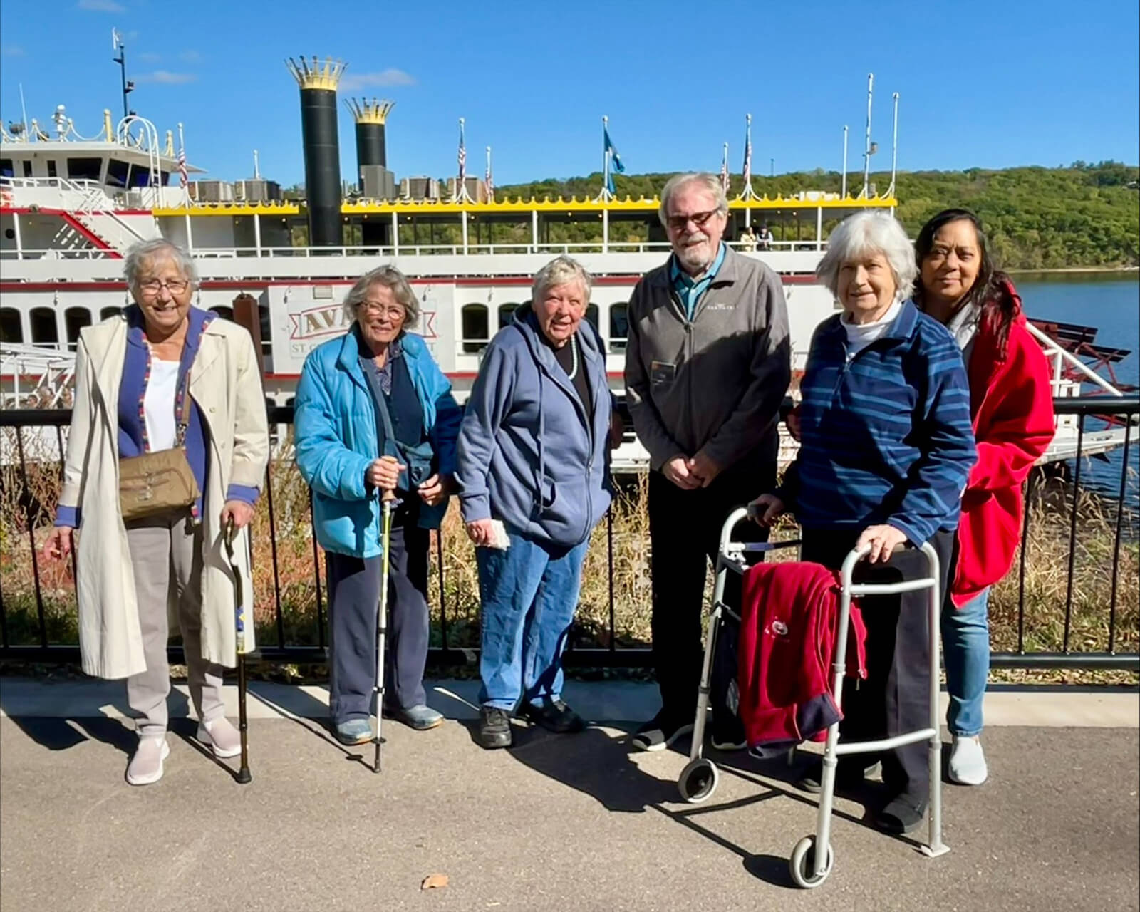 Residents of The Waters on 50th enjoying a sunny day outdoors in Minneapolis, with the iconic paddleboat in the background.