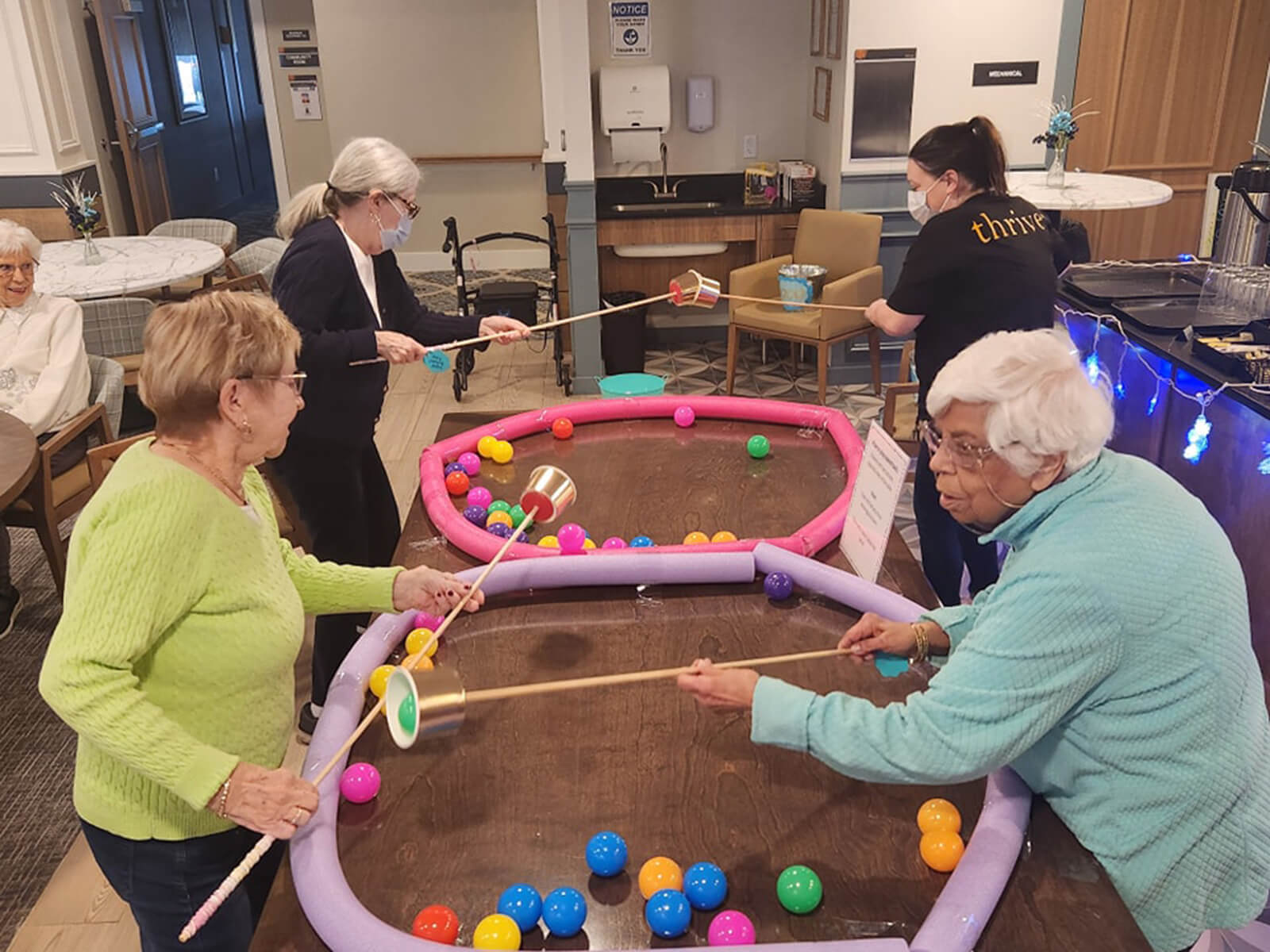 Seniors at The Waters of Pewaukee playing an adapted indoor croquet game, staying active and engaged with community life.