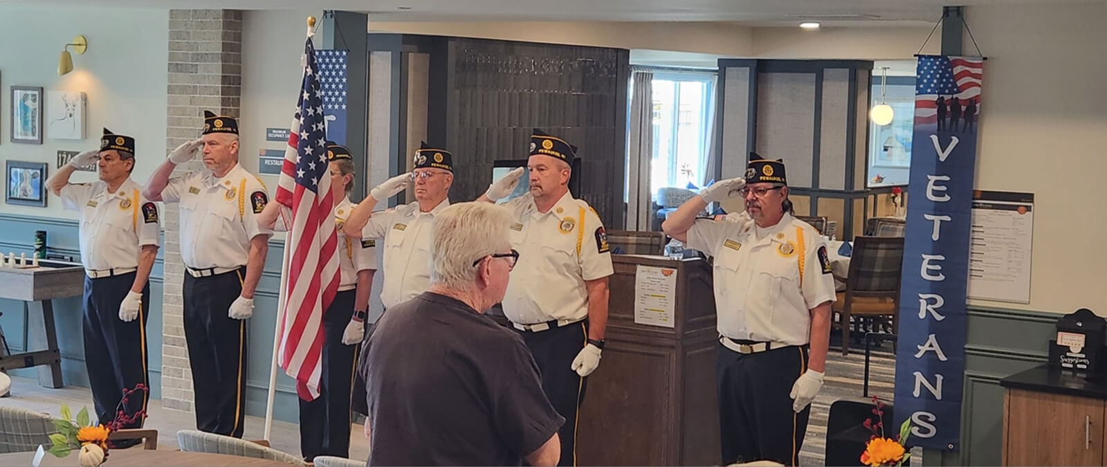 A solemn salute to the flag by veterans at The Waters of Pewaukee, representing the community's respect and honor for military service.