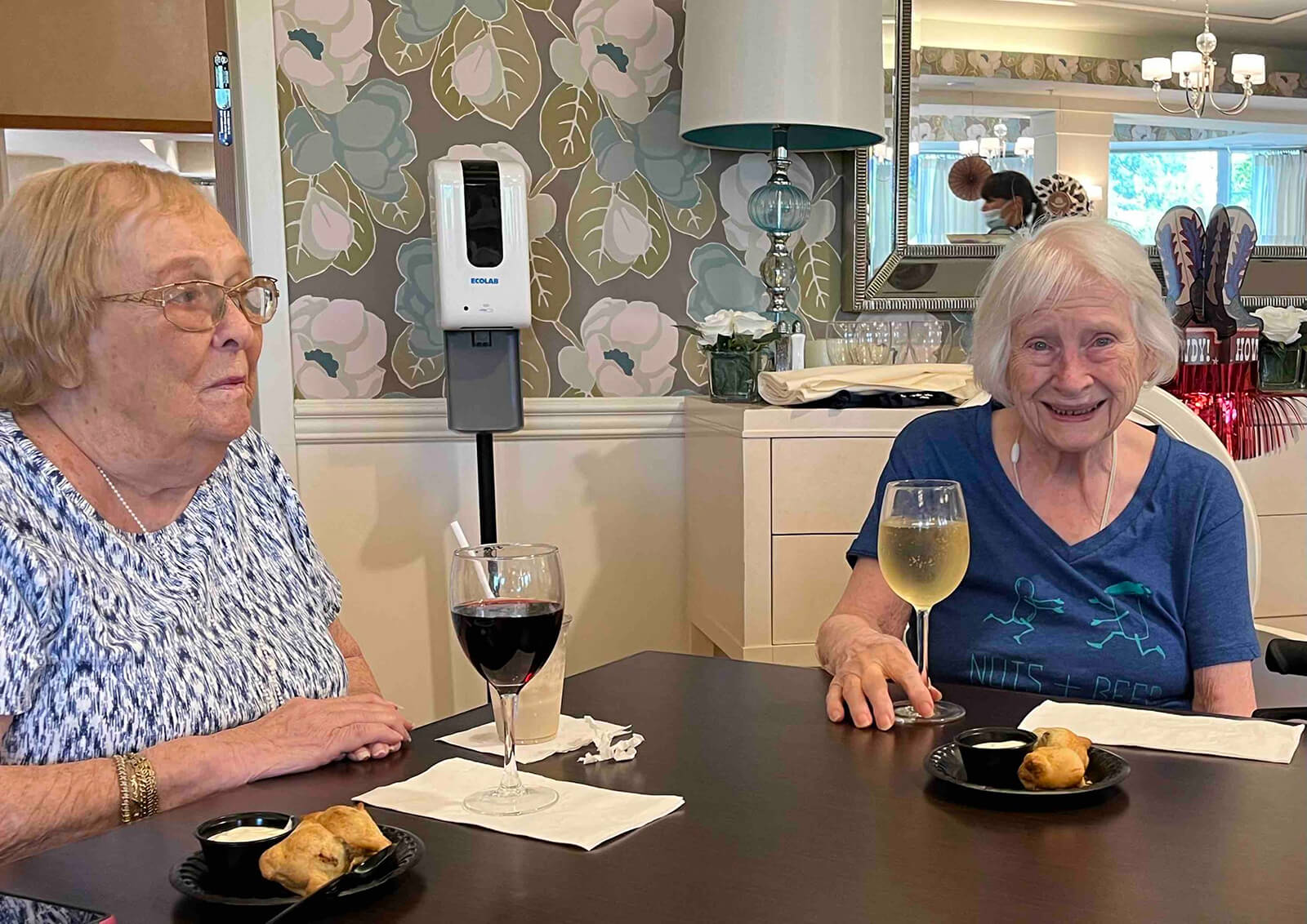 Residents at The Waters of Oakdale sharing stories over wine and appetizers during a social dining event, promoting friendship and enjoyment.